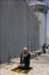 فلسطينية تصلي أمام جدار الفصل العنصري في الضفة بعدما منعها جنود الاحتلال من دخول القدس لأداء صلاة الجمعة