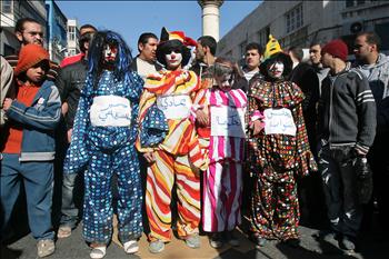أردنيون يرتدون أزياء مهرجين كُتب عليها مجلس النواب والحكومة وسمير الرفاعي خلال تظاهرة احتجاجاً على ارتفاع الأسعار في عمّان أمس