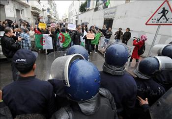 عناصر من الشرطة الجزائرية يغلقون أحد الطرق لمنع المحتجين من القيام بمسيرة في العاصمة الجزائر أمس الأول