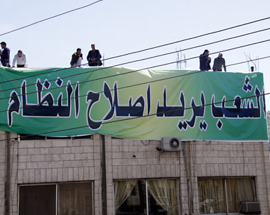 المتظاهرون يثبتون شعار "الشعب يريد إصلاح النظام" على عمارات بوسط عمّان