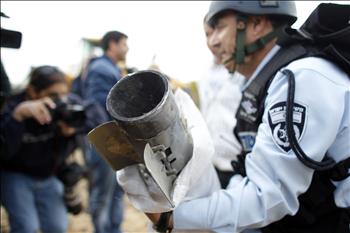 شرطي إسرائيلي يحمل بقايا صاروخ «غراد» سقط في أسدود أمس