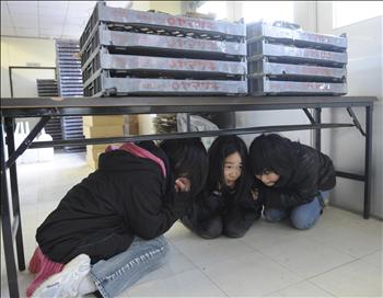 ثلاث فتيات يختبئن تحت طاولة أثناء هزة قوية ضربت اليابان أمس في أيمشيوفاكي 