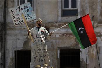 ليبي يرفع علم الثورة ولافتة كُتب عليها لا وجود للقاعدة و»حزب الله» في ليبيا خلال صلاة الجمعة في بنغازي أمس