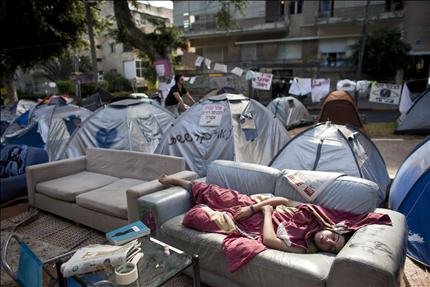 إسرائيلية تنام على كنبة في منطقة «ثورة الخيام» في تل ابيب امس (رويترز) 
