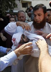 فلسطيني يحمل طفلاً استشهد في غارة إسرائيلية خلال تشييعه في رفح في قطاع غزة امس (ا ب) 