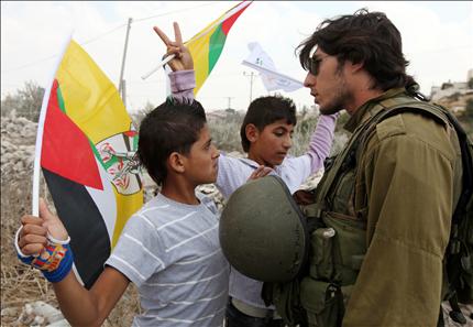فلسطينيان يواجهان جندياً إسرائيلياً خلال تظاهرة في قرية المعصرة في الضفة الغربية امس (ا ب ا) 