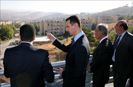 الأسد يتحدث مع مسؤولين ومدراء مشاريع خلال الاطلاع على مشاريع بناء طريق جديد حول دمشق (أ ف ب) 