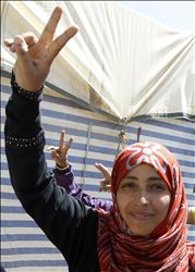 كرمان ترفع شارة النصر خارج باب خيمتها في ساحة التغيير، بعدالإعلان عن فوزها بالجائزة أمس (رويترز) 