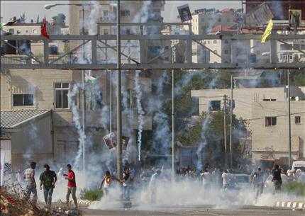 فلسطينيون يفرون من قنابل الغاز المسيل للدموع خلال اشتباكات مع قوات الاحتلال أمام سجن عوفر في الضفة الغربية أمس (أ ب) 