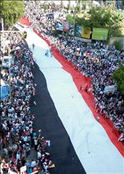 سوريون يحملون علماً ضخماً لبلدهم خلال تظاهرة دعم للأسد في اللاذقية أمس (أ ف ب) 