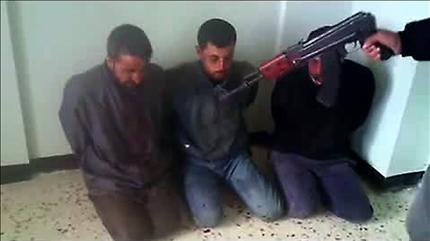 صورة مأخوذة عن شريط فيديو بث على «يوتيوب» في 4 اذار الحالي لمعارض مسلح يهدد 3 معتقلين من انصار النظام (ا ف ب) 
