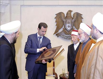 الأسد يتسلم نسخة من القرآن خلال استقباله وفد علماء الدين في دمشق أمس (رويترز) 