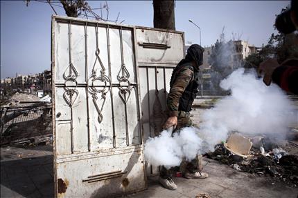 مسلح سوري يرمي قنبلة دخانية في حلب أمس (أ ب أ) 