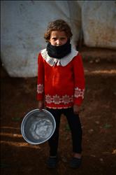 طفلة سورية نازحة تنتظر بالدور للحصول على طعام كمساعدة في مخيم معبر السلام في حلب قرب الحدود التركية امس الاول (ا ف ب) 