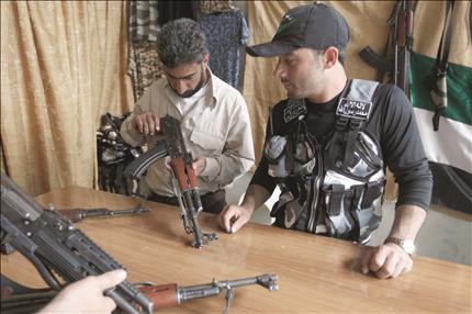 مسلح يتفقد كلاشينكوف قبيل ان يشتريه في حي الميسر في حلب امس (رويترز) 