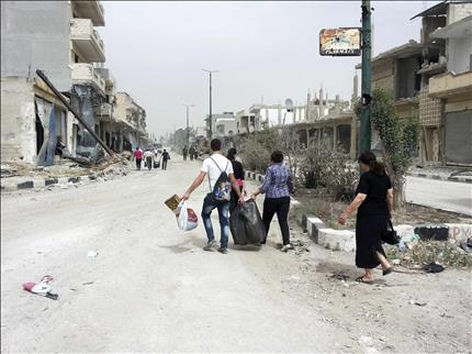 سوريون ينقلون اغراضا بعد تفقدهم منازلهم في القصير السبت الماضي (رويترز) 