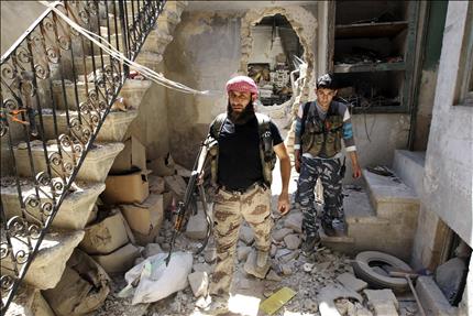 مسلحان داخل منزل تضرر جراء الاشتباكات في حي باب الناصر في حلب امس (رويترز) 
