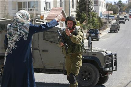 فلسطينية تصرخ في وجه جندي إسرائيلي خلال حملة اعتقالات وتفتيش شنتها قوات الاحتلال في رام الله في الضفة الغربية أمس (أ ب) 