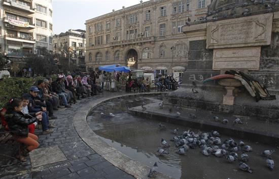سوريون يجلسون في ساحة المرجة في دمشق امس (رويترز)