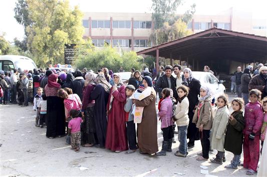 سوريون يتجمعون في احد المراكز الحكومية في دمشق بعد فرارهم من عدرا استعدادا لنقلهم الى مراكز الايواء (رويترز)