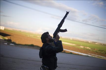 مسلح يوجه سلاحه باتجاه طائرة حربية سورية في قرية فافين في ريف حلب أمس (أ ب) 