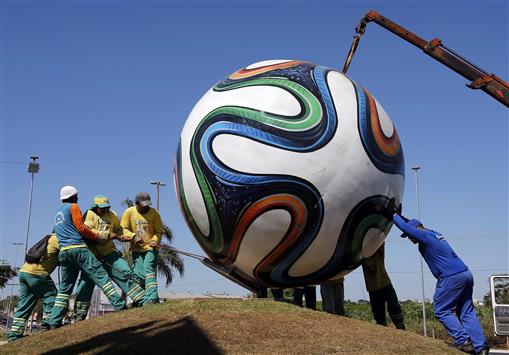 عمال يثبّتون كرة عملاقة في مدينة كويبا استعدادا لانطلاق «المونديال» اليوم (رويترز)