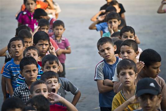 أطفال فلسطينيون يصطفون في باحة مدرسة للـ"أونروا" في غزة أمس (أ ف ب)