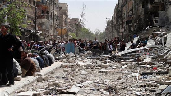 سكان يتجمعون في أحد أحياء مخيم اليرموك في دمشق (رويترز)