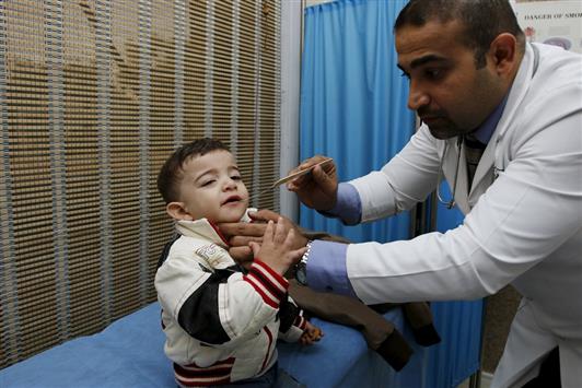 طبيب يُقدّم الرعاية الصحيّة لطفل نازح من بطش "داعش" إلى بغداد. (رويترز)