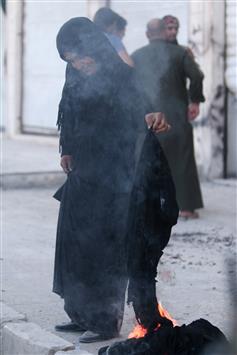 امرأة تحرق النقاب بعدما خرجت من مناطق سيطرة "داعش" في منبج (رويترز)