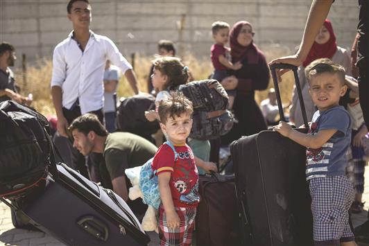 لاجئون سوريون يعودون من تركيا إلى مدينة جرابلس السورية عبر معبر قرقميش في منطقة كيليس أمس (أ ف ب)