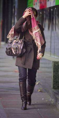 امرأة تغطي وجهها من كاميرات المصورين وهي تسير في شارع بطهران يوم السبت.