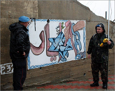 جنديان دوليان يعاينان الملصق الذي استهدفته طلقات الجندي الإسرائيلي