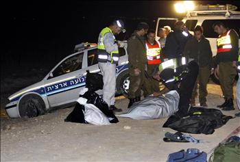 عناصر من الشرطة الإسرائيلية يعاينون جثة أحد العسكريين في موقع العملية قرب مستوطنة مسوا في وادي الأردن أمس