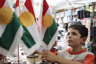 طفل ينظر إلى الأعلام الكردية بأحد المكتبات في أربيل