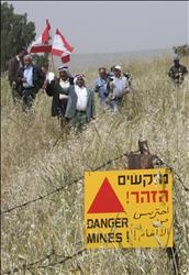 مجموعة من أهالي العباسية يرفعون العلم اللبناني بعدما أزالوا الأسلاك الشائكة التي وضعها الإسرائيليون في أرضهم قرب حقل ألغام إسرائيلي