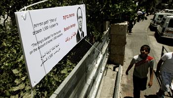 طفلان فلسطينيان يمران أمام لافتة كتب عليها خطة «نير بركات (رئيس بلدية الاحتلال في القدس): حديقة الملك لترفيه السياح على حساب 1500 فلسطيني» في حي سلوان أمس