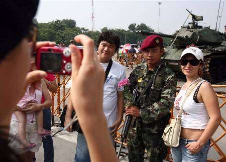 رجل وامرأة يلتقطان صورا مع جندي تايلاندي في بانكوك يوم 23 سبتمبر ايلول 2006