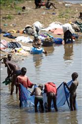 أطفال من جنوب السودان يصطادون السمك فيما نساء يغسلن الثياب في مياه نهر النيل في مدينة جوبا أمس الأول