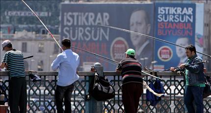 اتراك يصطادون السمك امام لافتة اعلانية لأردوغان في اسطنبول أمس (ا ب ا) 