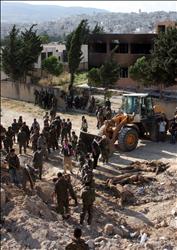 عناصر من القوات السورية بنتشلون امس جثث زملاء لهم من مقبرة جماعية عثر عليها في جسر الشغور (ا ب ا) 