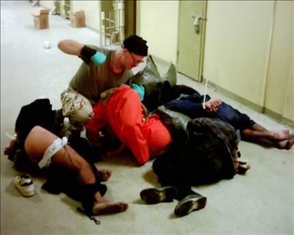 غرانر يعتدي على عدد من المعتقلين المكبّلين والمرميين على الأرض في سجن أبو غريب، في صورة تعود إلى العام 2003 (أ ب) وفي الاطار صورة لغرانر في مجمع «فورت هود» (أ ب) 
