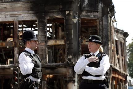 شرطيان بريطانيان يقفان امام احد المباني المحترقة جراء الشغب في توتنهام امس (ا ب ا) 