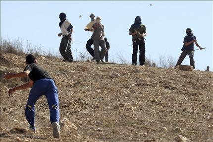 فتى فلسطيني (إلى اليسار) يتبادل رشق الحجارة مع مستوطنين اعتدوا على ممتلكات الفلسطينيين في قرية في الضفة الغربية (أ ب) 