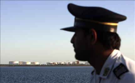 رجل أمن إيراني يراقب خزانات نفطية في مدينة شابهار شرقي مضيق هرمز أمس (رويترز) 
