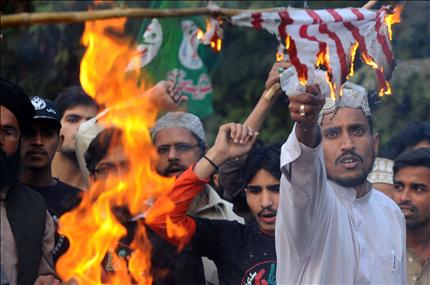 اسلاميون باكستانيون يحرقون علمي اميركا والناتو خلال تظاهرة في لاهور امس (ا ف ب)