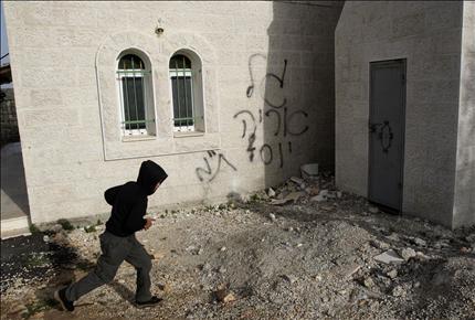 فتى فلسطيني يمر أمام مسجد دير استيا الذي هاجمه المستوطنون أمس (أ ب) 