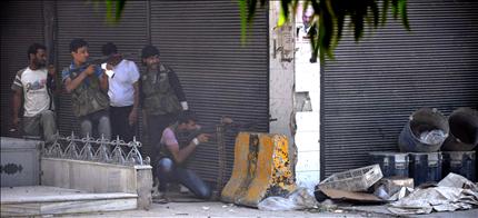 مسلحون سوريون يطلقون النار خلال اشتباكات مع القوات الأمنية في حي الشعار في حلب أمس (أ ف ب) 