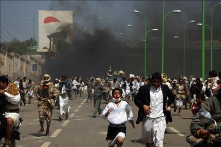 يمنيون يهربون من قنابل الغاز المسيل للدموع خلال الاشتباكات مع قوات الأمن بالقرب من السفارة الأميركية في صنعاء أمس. (أ ف ب) 