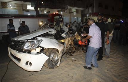 فلسطينيون يعاينون حطام السيارة التي استهدفتها الغارة الإسرائيلية على غزة، أمس (رويترز) 